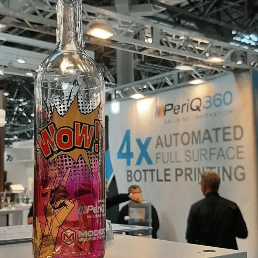 Mit Peri@360 bedruckte Klarglasflasche auf einem Messestand von Modico Graphic Systems
